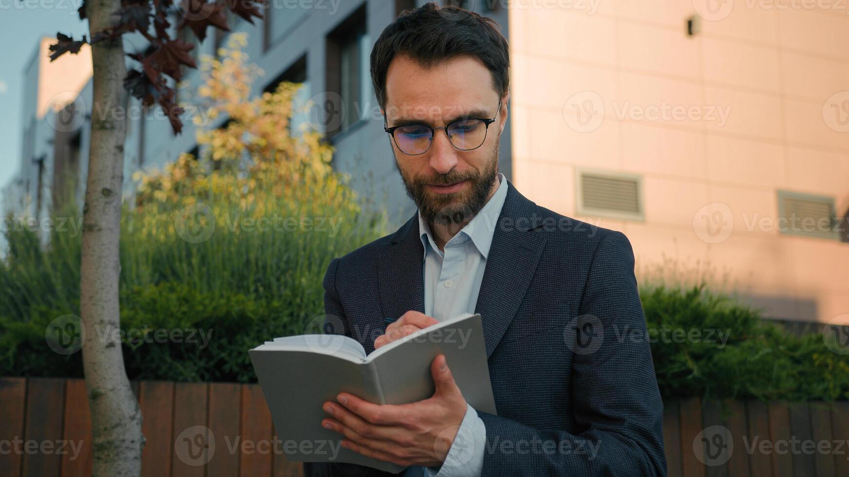 Thoughtful pensive man Caucasian businessman business coach in city write notes in notebook university professor writer thinking writing ideas at paper notepad smiling prepare for class lesson outside photo