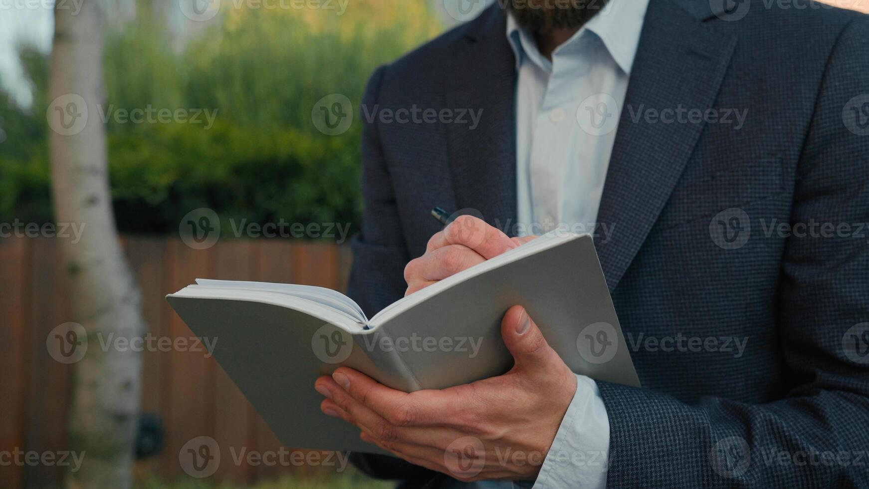 Thoughtful Caucasian man university professor lecturer prepare for class lesson college education write notes outdoors in city businessman writing business ideas at paper notebook thinking thoughts photo