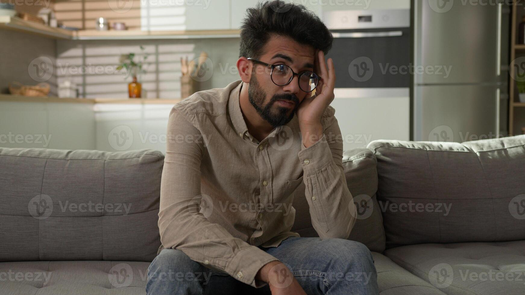 Pensive Indian Arabian man bored on home couch thinking deep in thoughts difficult decision tired exhausted thoughtful worried male boring weekend feel headache problem solution depression melancholy photo