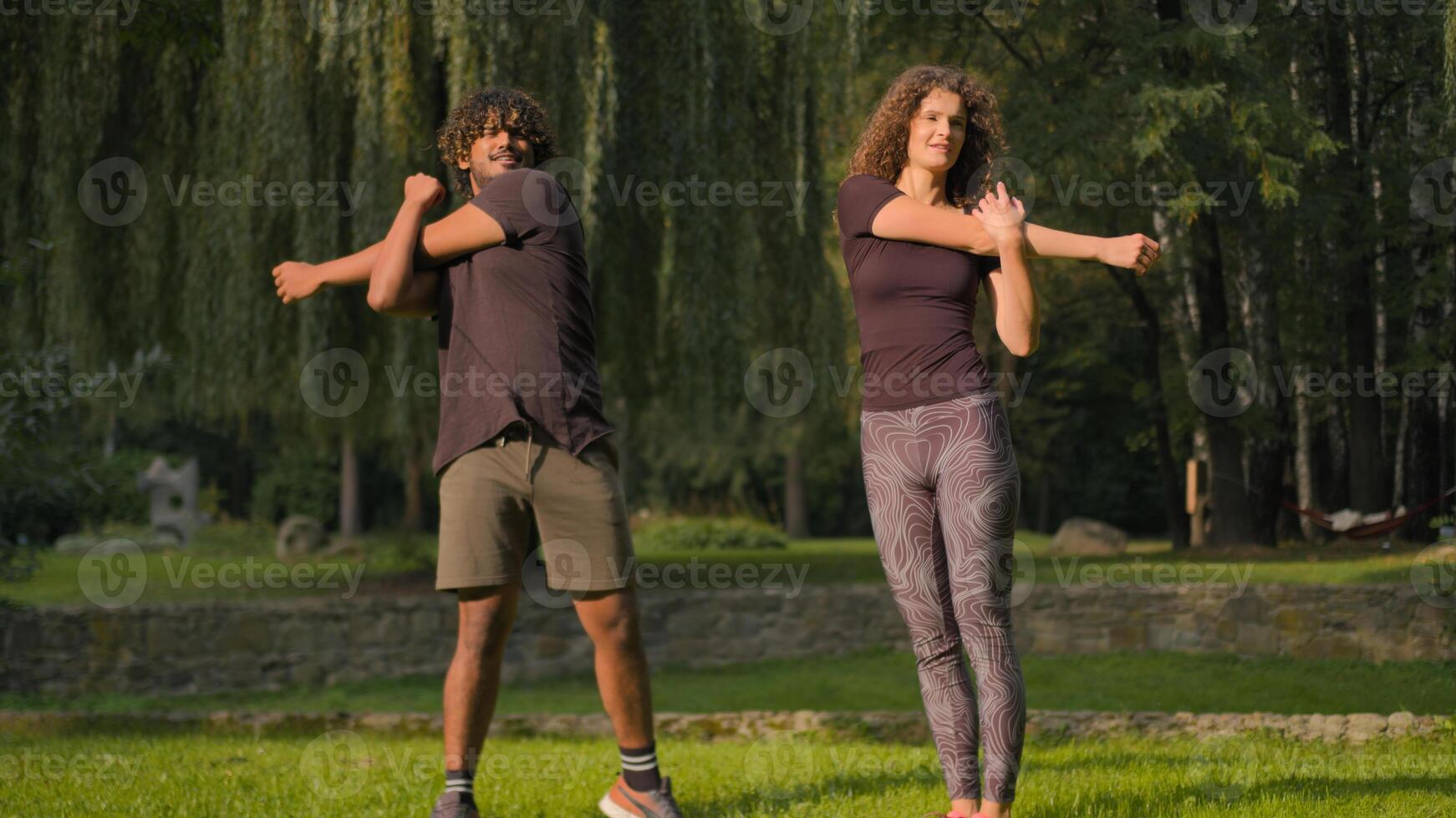 Healthy morning fitness in park nature multiracial couple Indian Arabian man personal trainer Caucasian woman training pair workout outdoors arms stretching stretch hands muscles together sport love photo