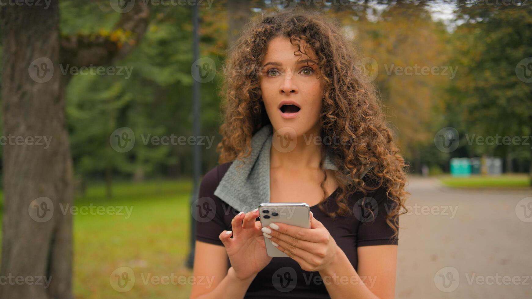 Happy Caucasian young gen z woman amazed shocked fitness girl with mobile phone smartphone shout yes winning prize online sport bet champion female sportswoman win celebrate victory in city outdoors photo