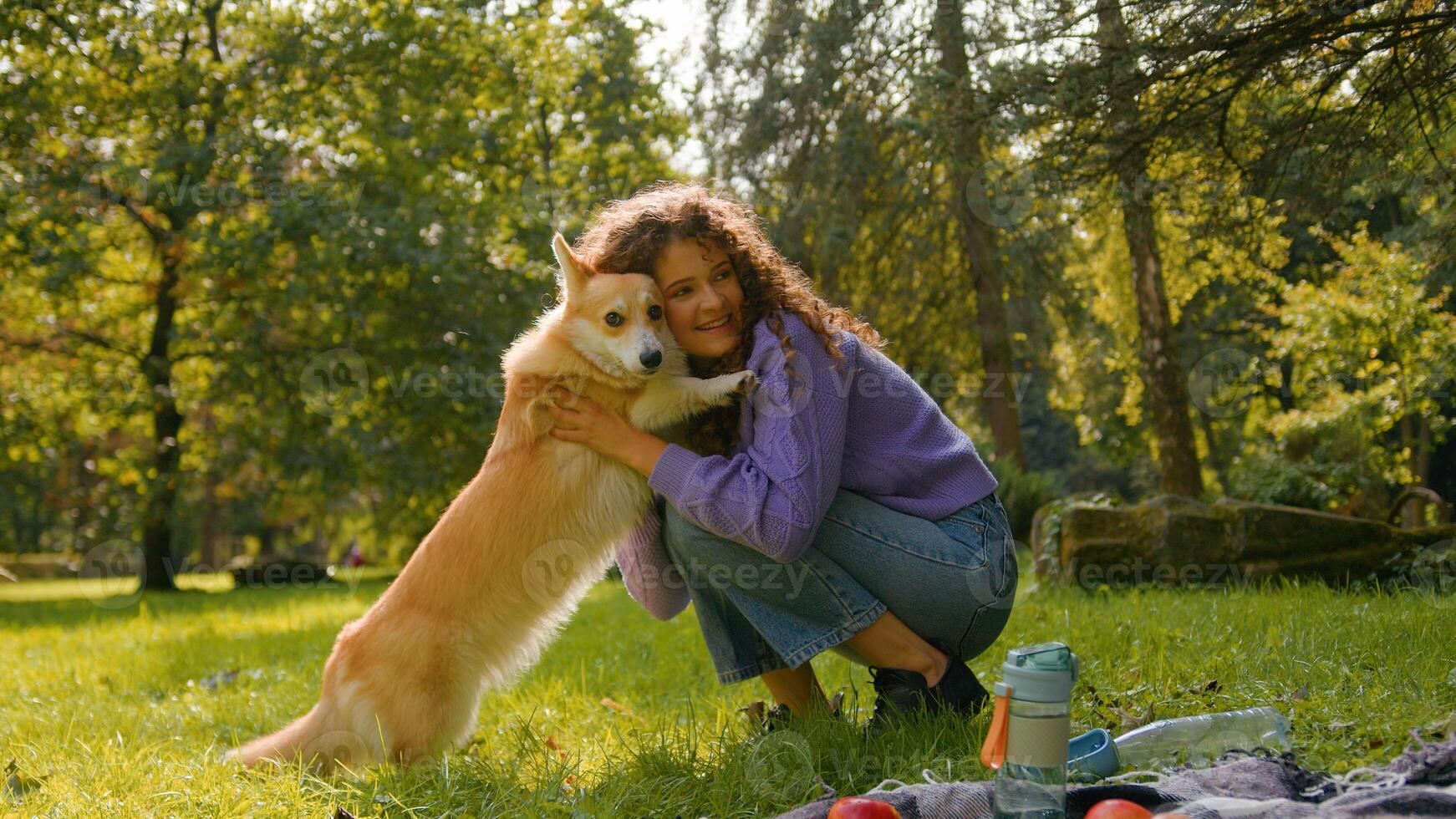 Happy joyful Caucasian woman playing with smart little dog pembroke welsh corgi in pets friendly park summer city young girl hugging cute golden fluffy puppy pet and owner love human animal friendship photo