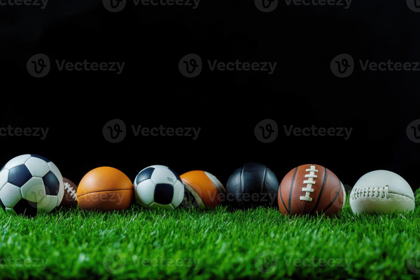 Various sports balls arranged on green grass with a dark background highlighting their different designs and materials photo