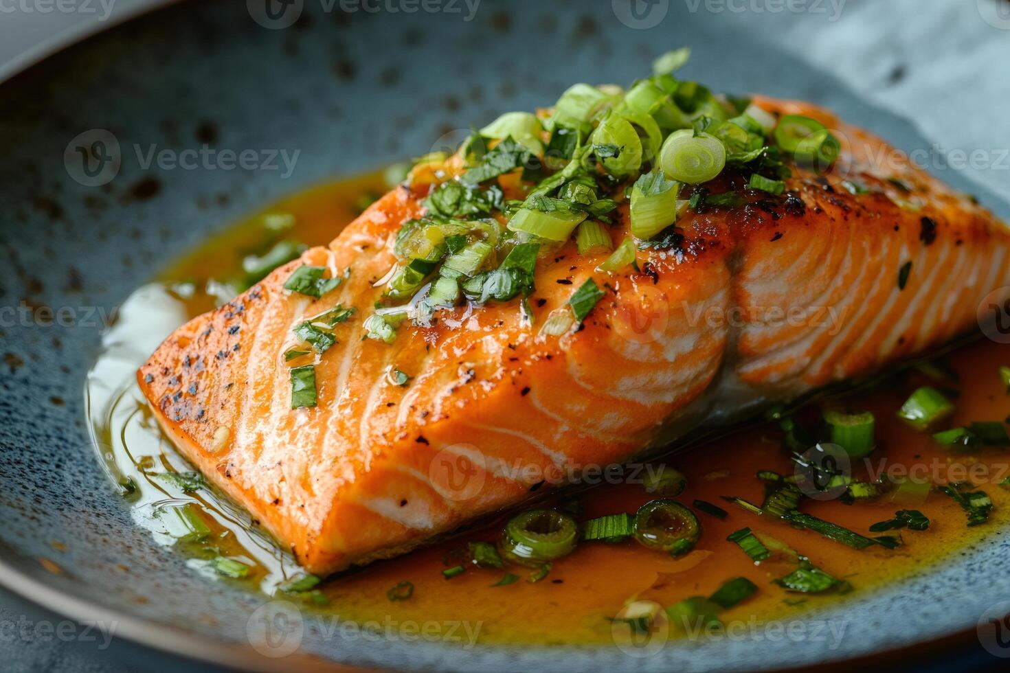 Grilled salmon fillet with spring onions and savory sauce on modern plate photo