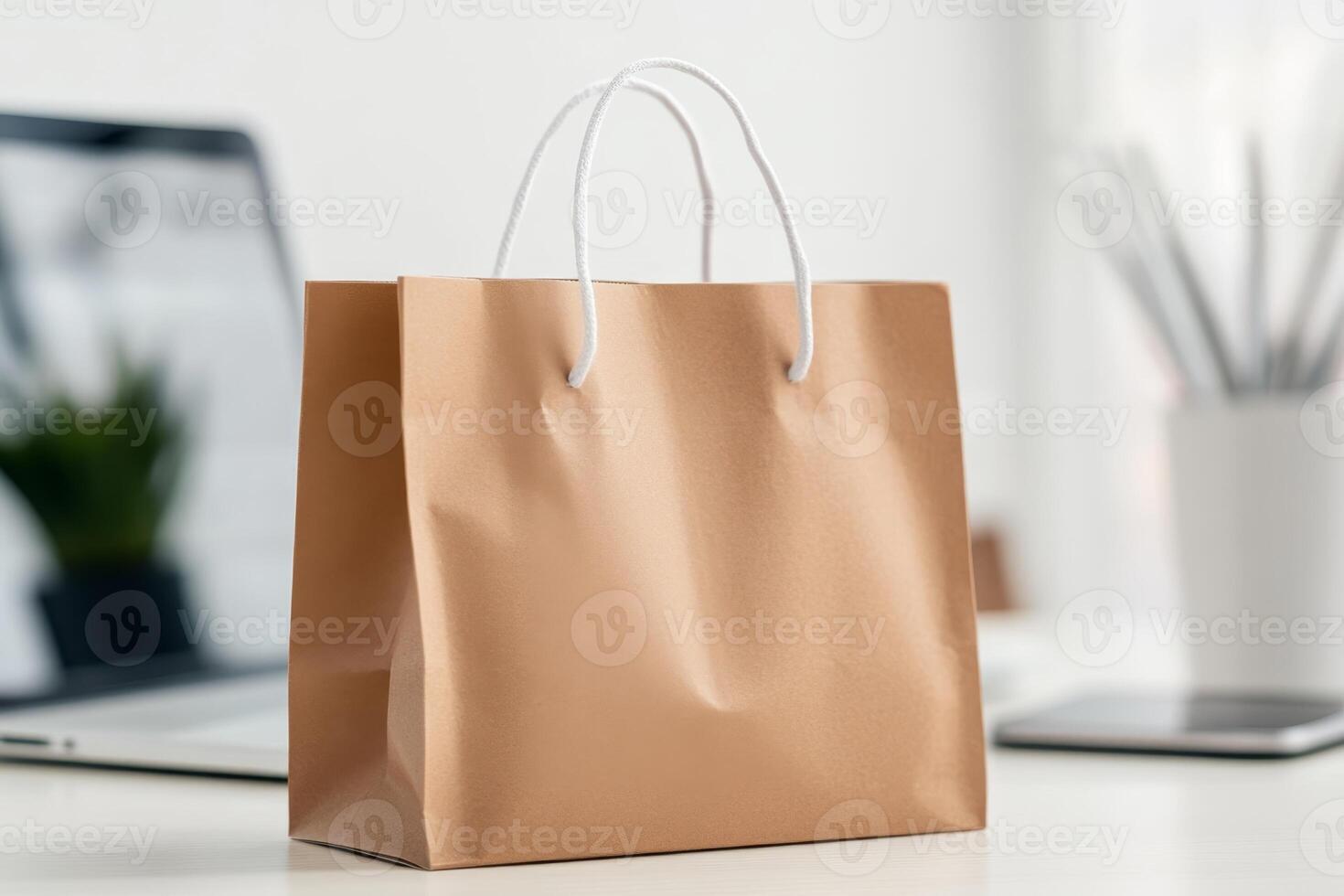 Simple brown paper shopping bag on a desk with modern office accessories and technology visible in the background photo