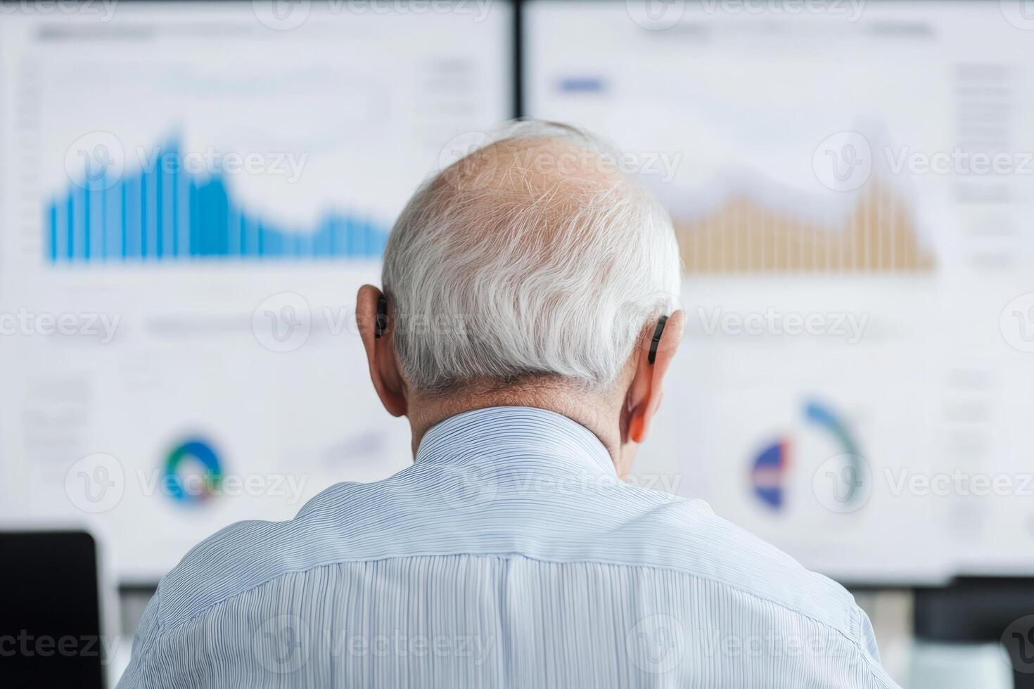 Senior analyst reviewing business performance metrics on digital screens in a modern office setting photo