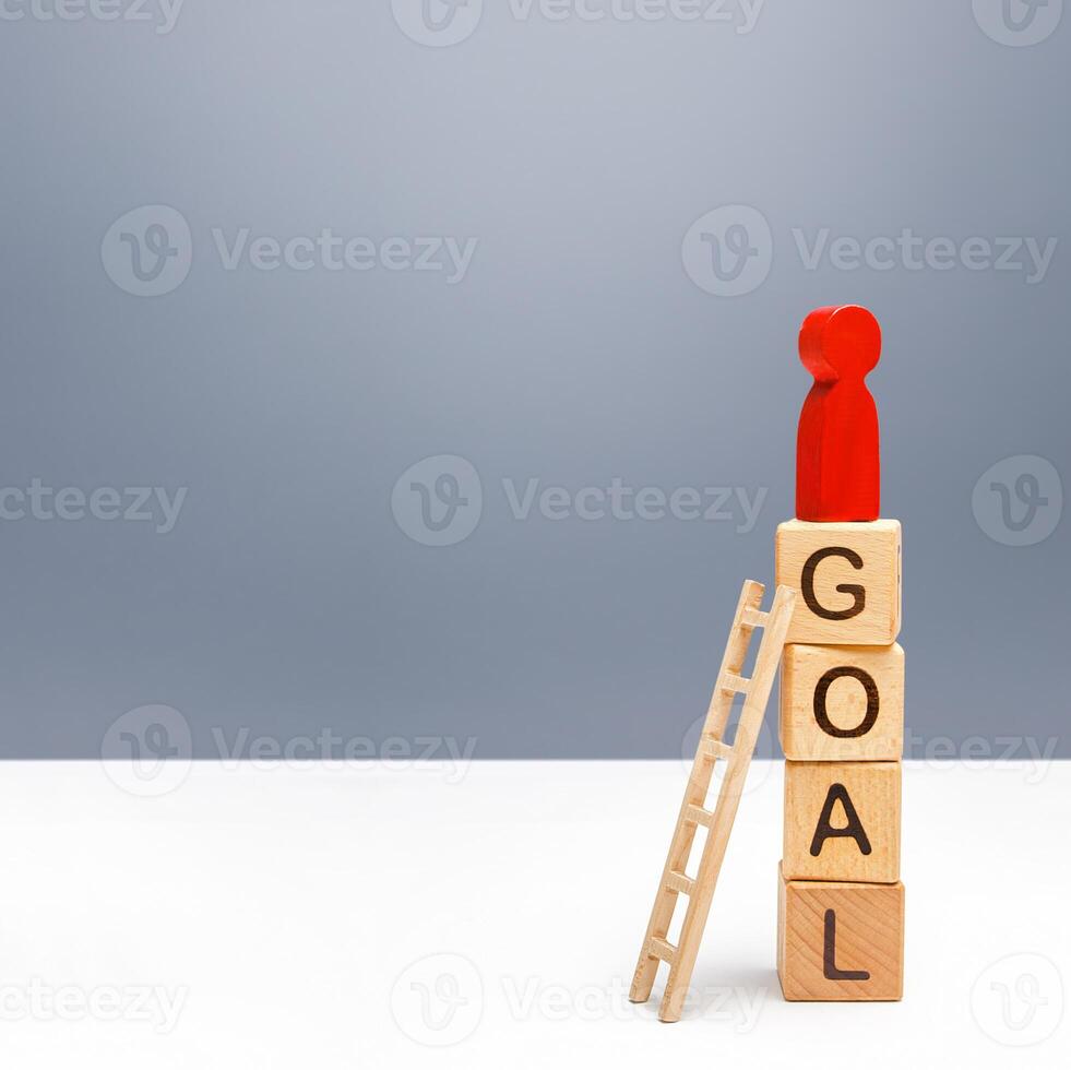 The red person climbed a tower of GOAL blocks. Developing strategy. Attracting investment and financial resources for a successful business startup. Using tools to solve problems, achieve success. photo