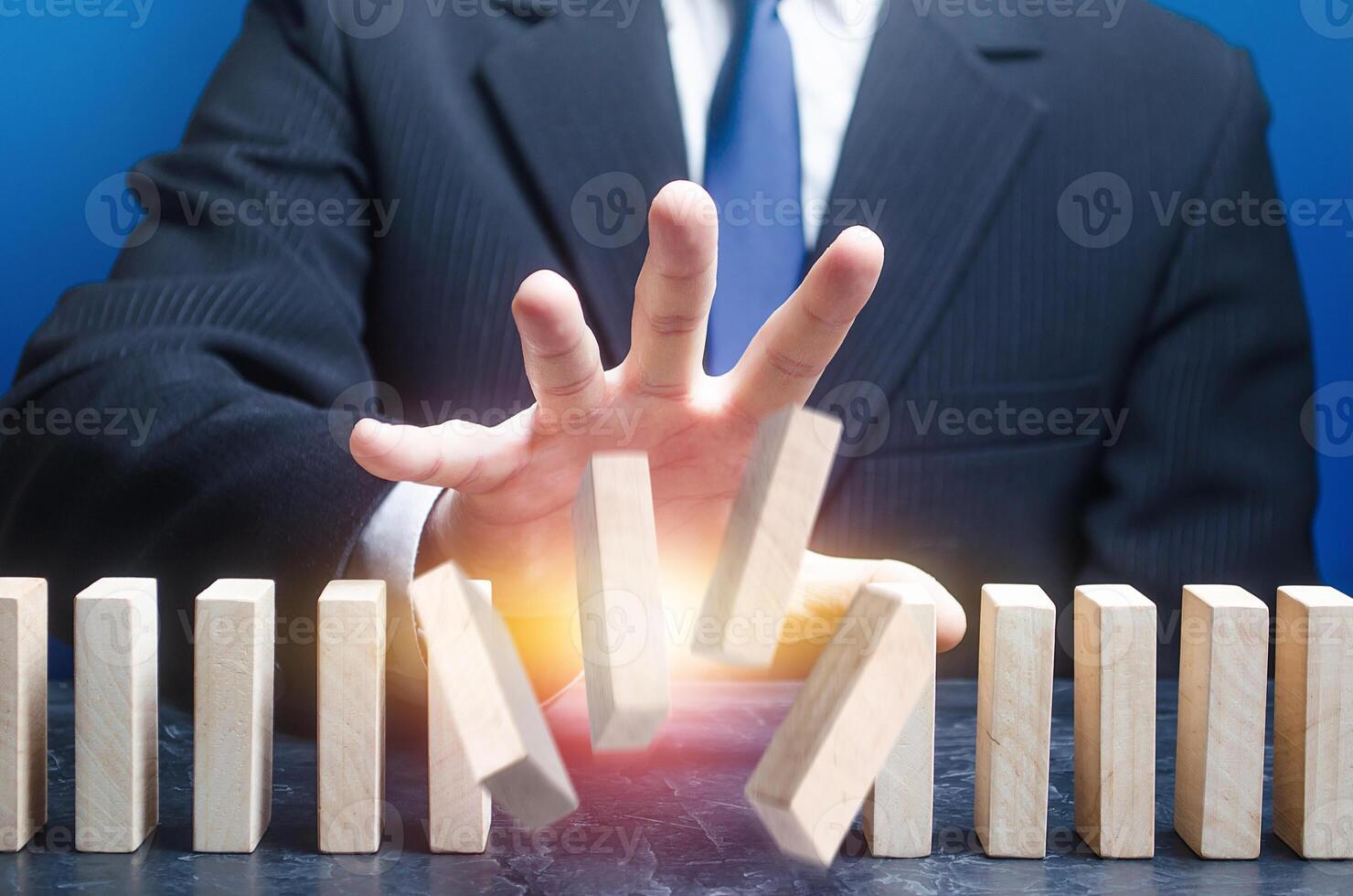 Man destroys order of standing domino row. Spoil plans, ruin business processes. Instability, hit a weak point. Sabotage, ruin a competitor's company. Crime, destabilization of situation, break rules. photo