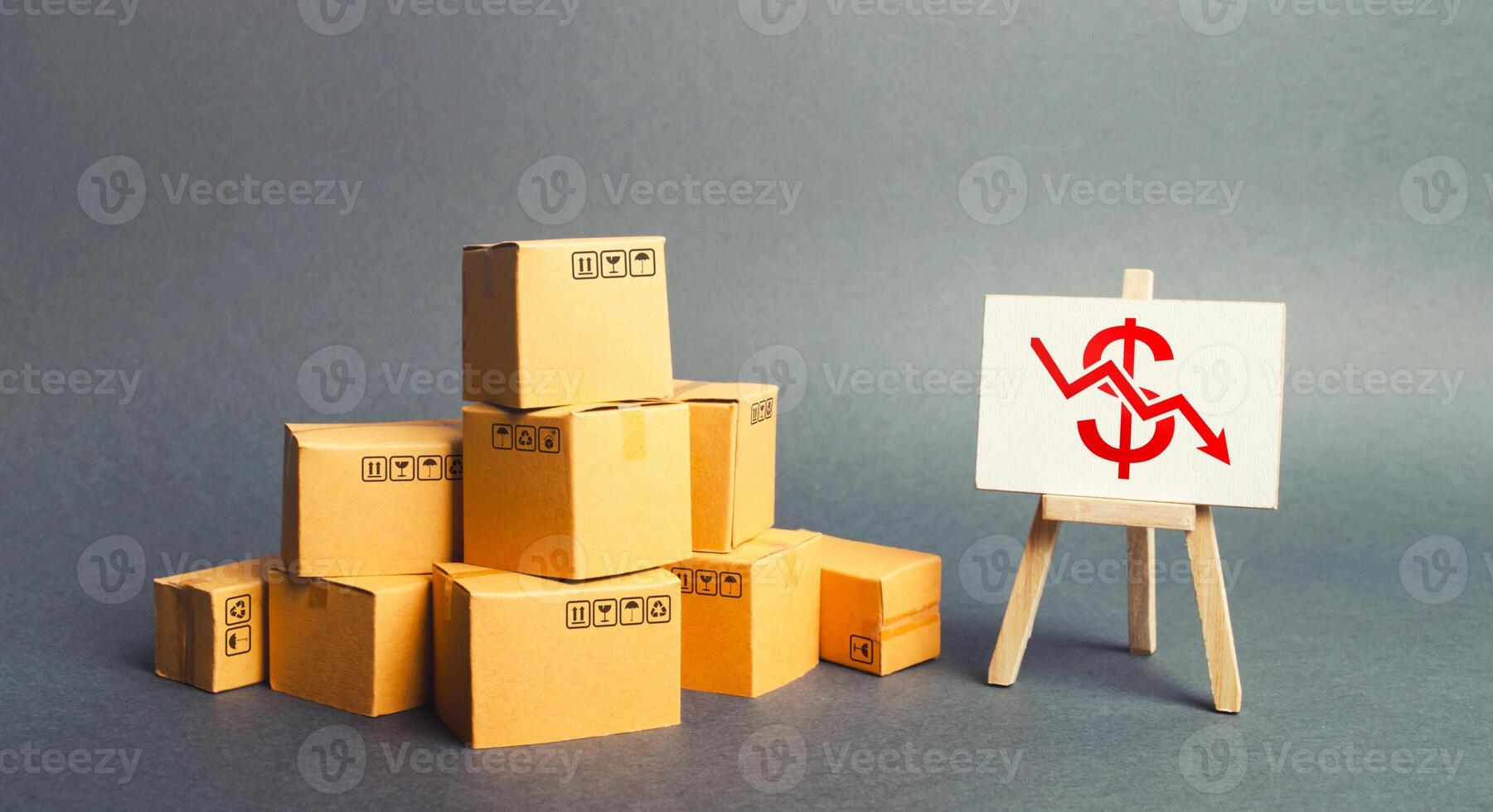 Pile of boxes and easel with dollar red arrow down graph chart. Drop in profits, slowdown in sales. Fall in imports or exports, trade deficit. Low productivity and high costs. Industrial production. photo