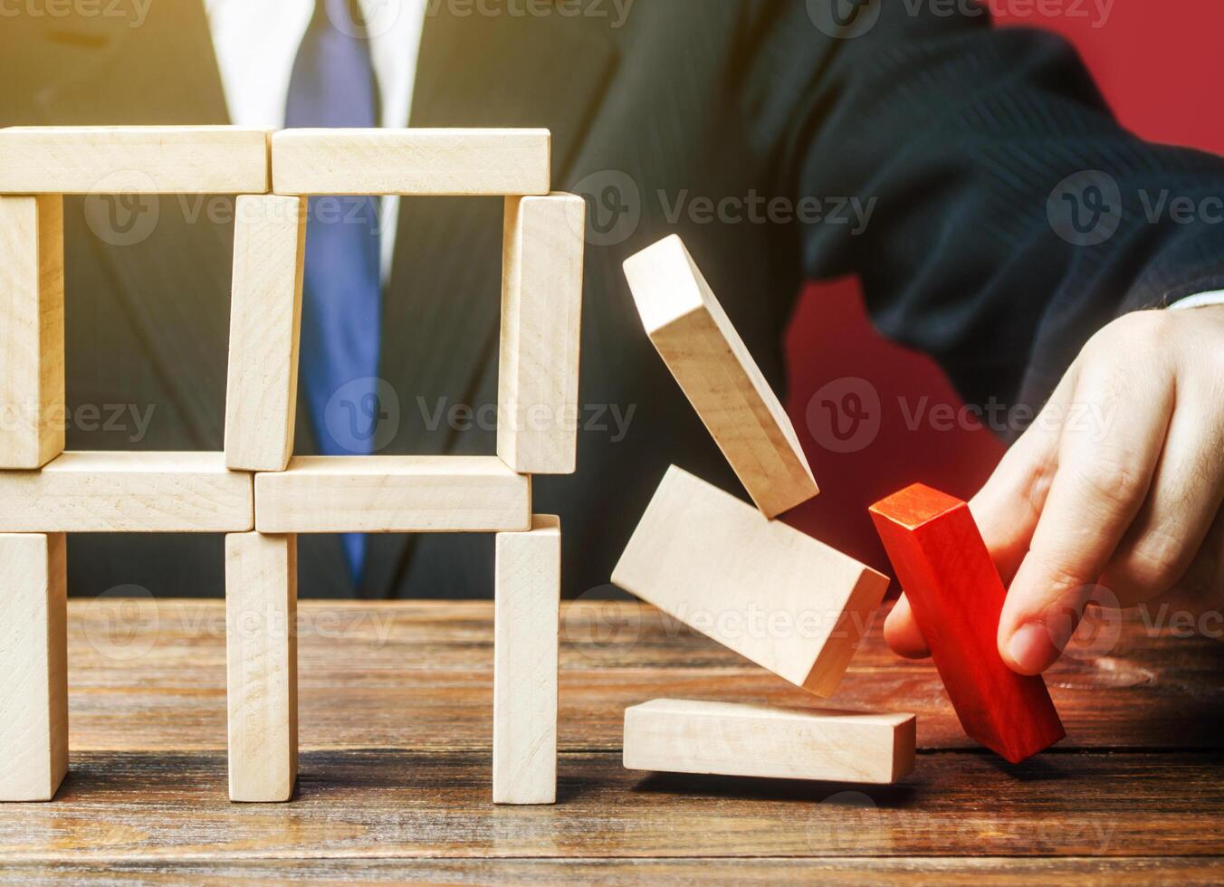 A businessman removes an important component causes collapse of entire complex system. Incompetent businessman. Inexperience, unprofessional leader. Failure. Making wrong decisions, ruining business. photo