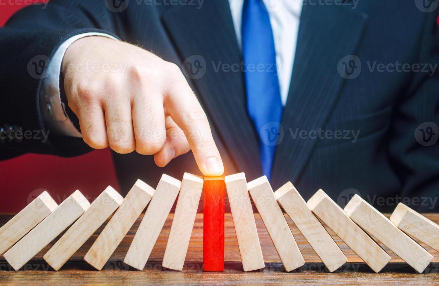 Businessman with a touch stops process of falling dominoes. Risk management concept. Successful strong business, problem solving. Stop destructive processes. Strategy development. Debt restructuring photo