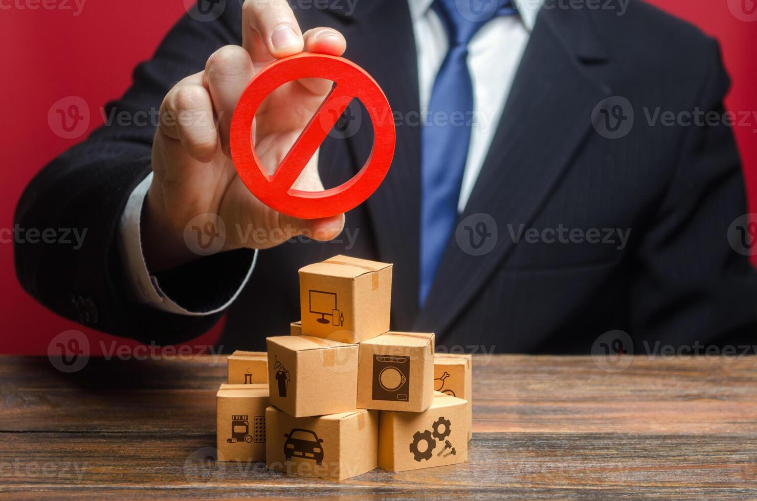 Businessman man official holding red prohibition sign NO over boxes with goods. Restriction import, ban export of dual use goods to countries under sanctions. Out of stock. Embargo trade wars. photo
