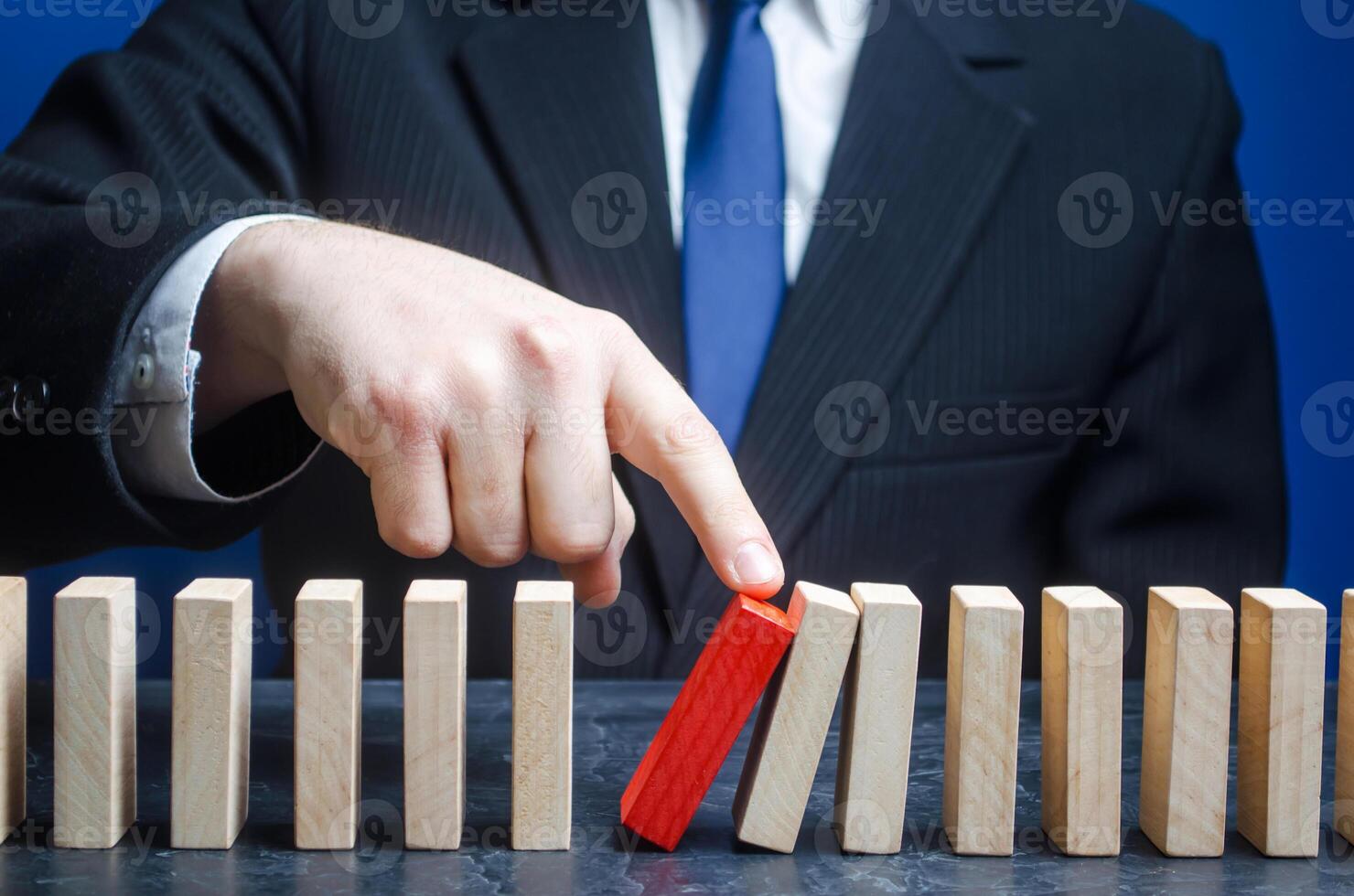 Businessman starts the process of falling dominoes. Starting work after stopping. Continuation of working, obstacle avoidance. maintainability. Correction of errors and malfunctions photo