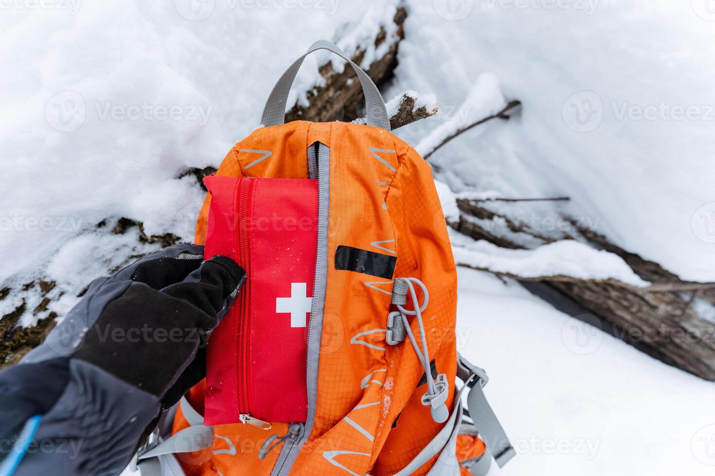 A determined individual stands in thick snow, confidently holding a reliable backpack with a stocked first aid kit, ready for any emergencies during their winter adventure photo