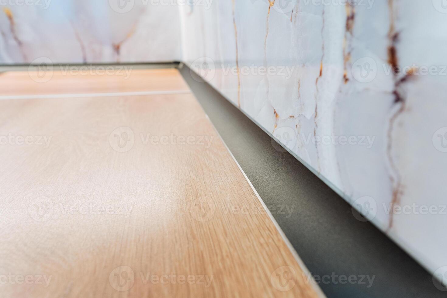 This image presents a closeup of a beautifully crafted wooden floor with intricate details, complemented by a stunning marble wall in the background, creating a harmonious environment photo
