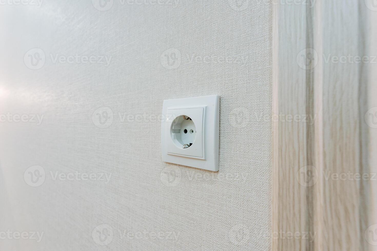 This is a detailed closeup photograph showing a white electrical outlet mounted securely on a wall, highlighting its design and functionality in relation to home electrical systems photo