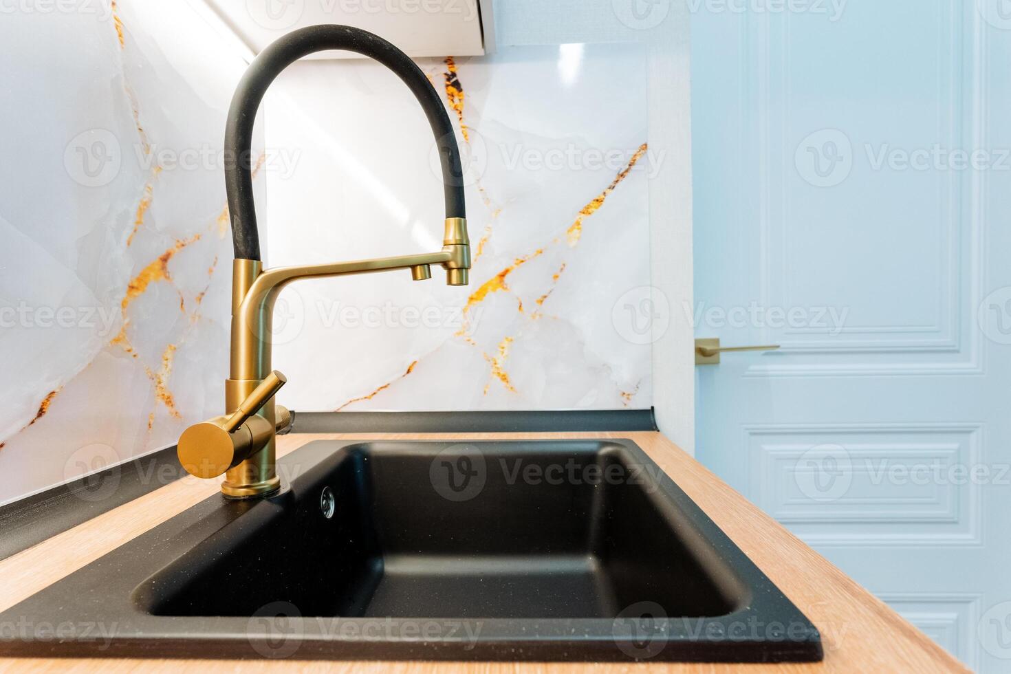 A beautifully designed kitchen features an elegant black sink paired with a sleek gold faucet, enhancing aesthetic and sophistication, transforming the space into a stylish culinary haven photo