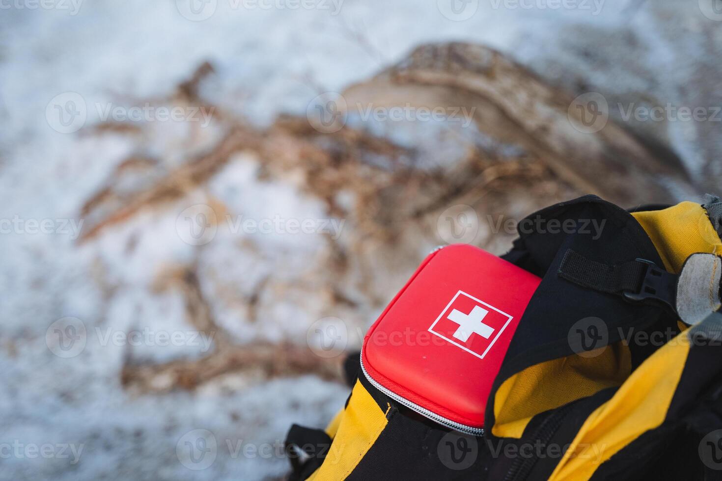 Nestled securely in the top compartment of a durable, sturdy yellow and black backpack, a compact first aid kit is at the ready, prepared for any unforeseen outdoor adventure that may arise photo