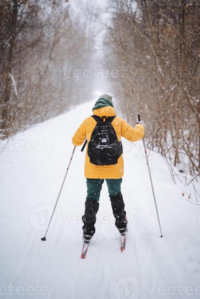 A person is expertly skiing down a beautiful, snowcovered path that winds through the serene woods, surrounded by tall trees. The scene is perfect for winter sports enthusiasts photo