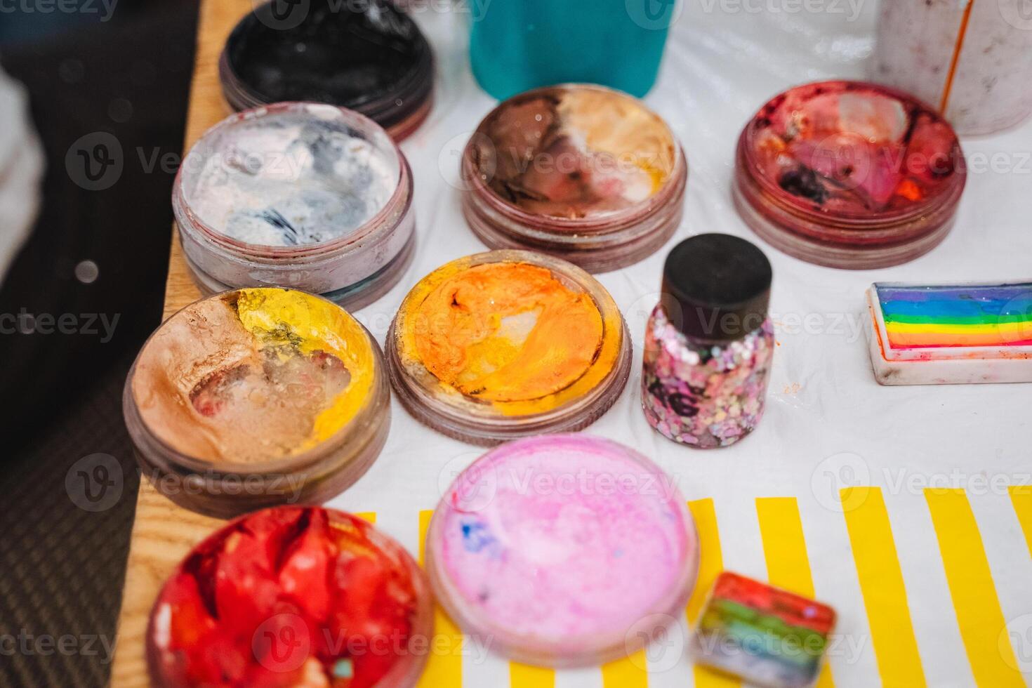 A beautifully arranged table adorned with vibrant face paints and colorful sprinkles, perfect for engaging in creative activities and artistic expression with friends and family photo