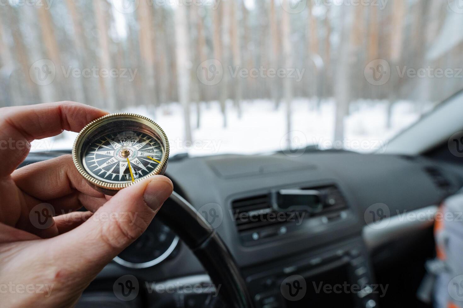 A person confidently holds a compass in their hand while sitting inside a car, likely intending to use it for navigation and to find the correct direction during their journey ahead photo