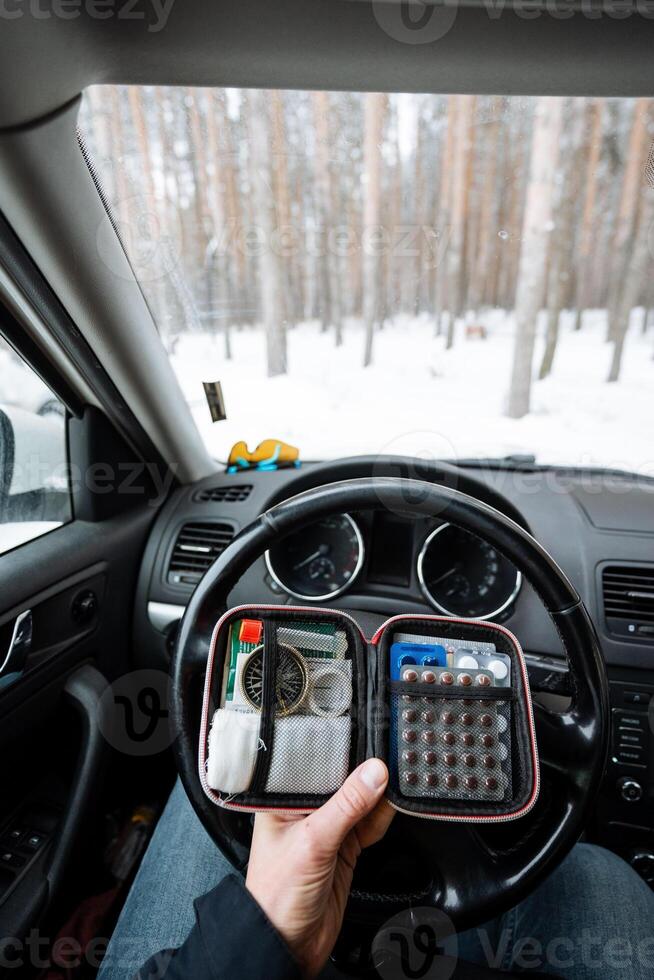 A person is comfortably sitting inside a parked car while holding a calculator in their hand, seemingly engaged in some calculations or planning on the device with focus and concentration photo