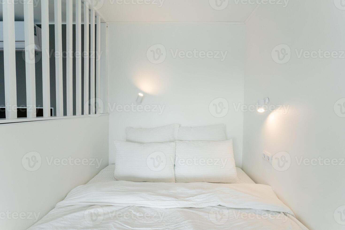 A cozy bed in a small room, adorned with white sheets and pillows photo
