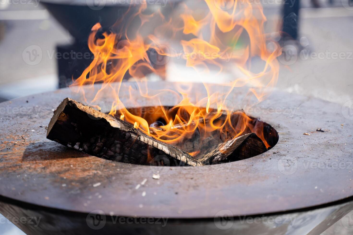 This image captures a striking closeup view of a vibrant fire burning within a sturdy metal bowl, showcasing the brilliant flames and glowing ash that dance within its confines photo