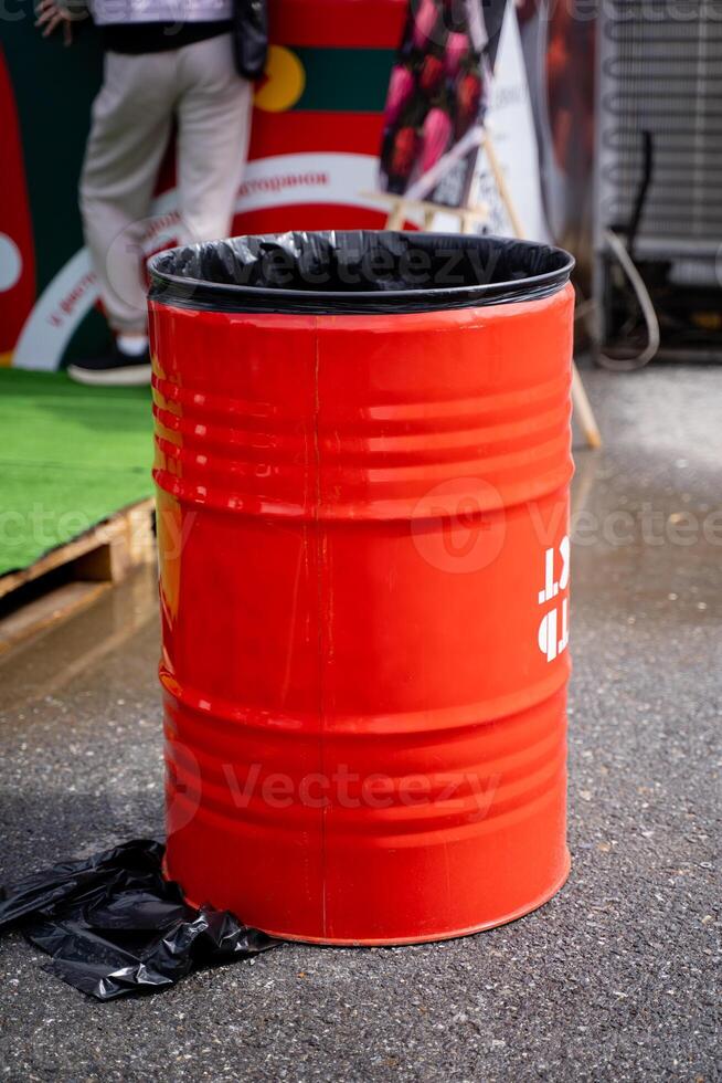 A bright red trash can is currently placed on the side of the road, likely waiting to be picked up by waste management services or disposed of properly at a designated location photo