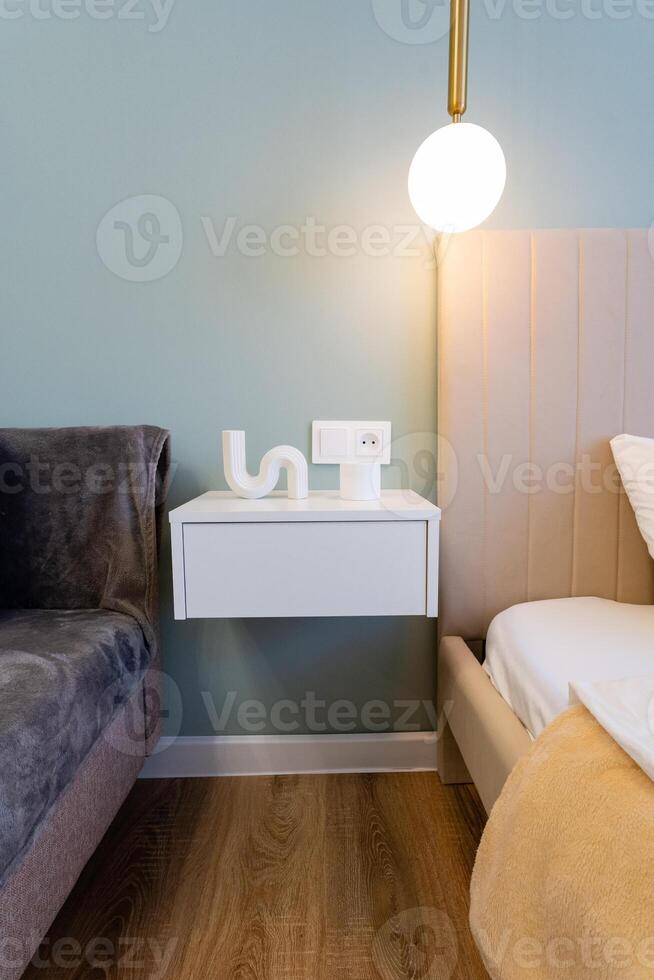 This beautifully crafted bedroom features a cozy bed, plush couch, trendy nightstand, and elegant lamp, creating a warm, inviting atmosphere perfect for relaxation and comfort photo