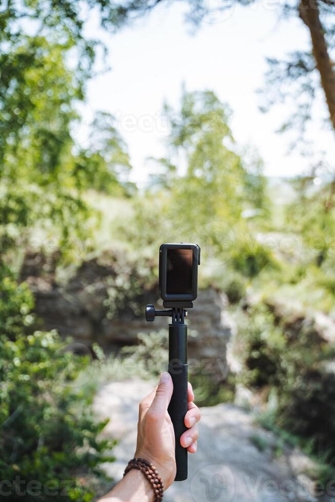 In a serene natural environment, a hand gripping a camera represents exploration and adventure in the wilderness with the aid of technology for capturing the beauty of nature photo