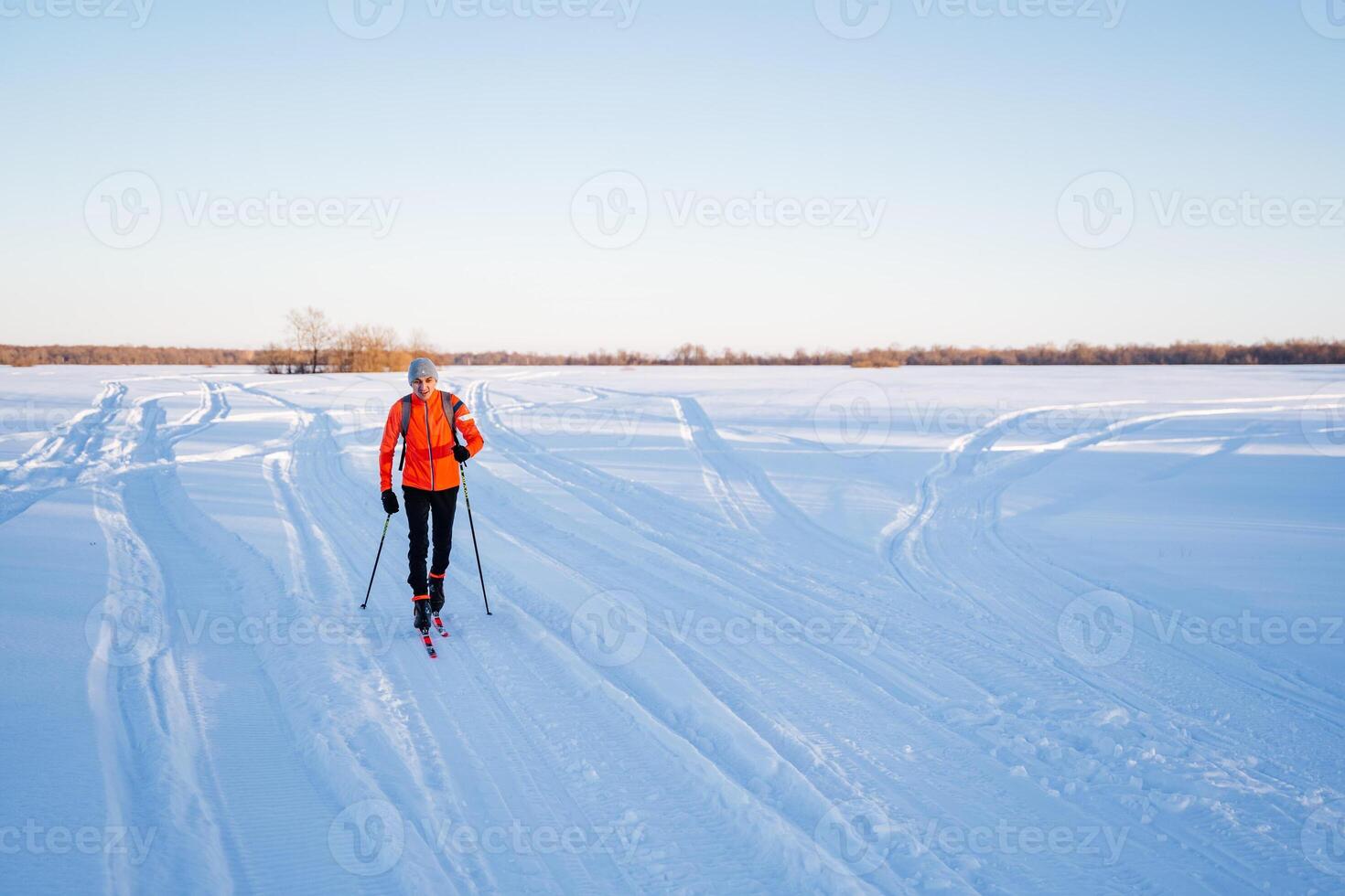 Skier running on rough terrain in the shade of trees at sunset, skiing training on the field. photo