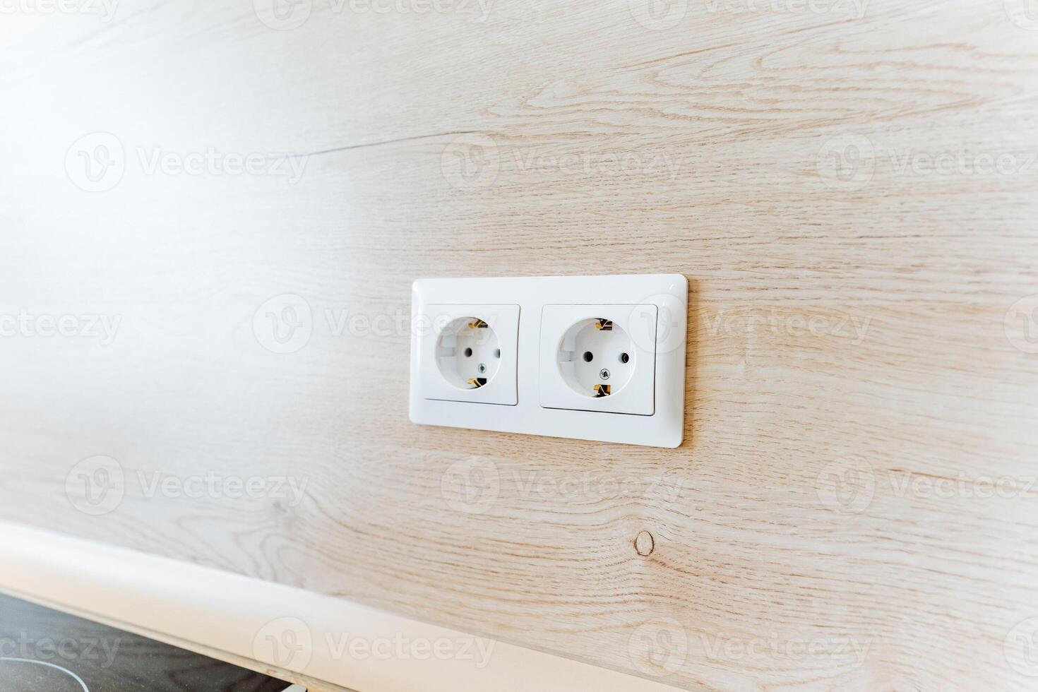 Two white wall sockets installed on a hardwood wall photo