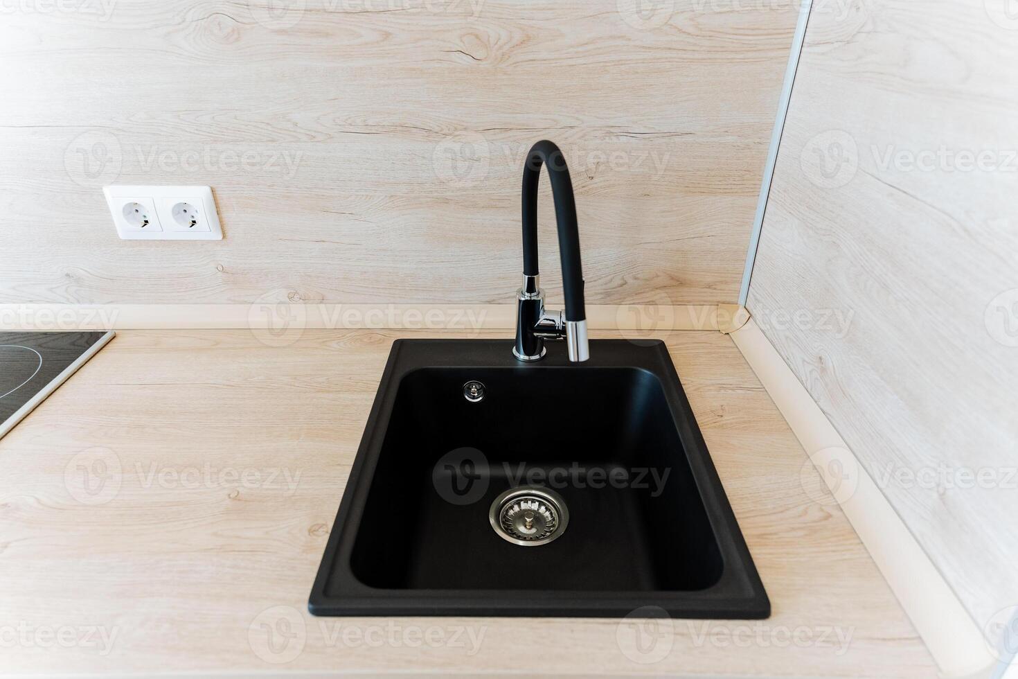 Black kitchen sink and faucet on wood countertop in the kitchen photo