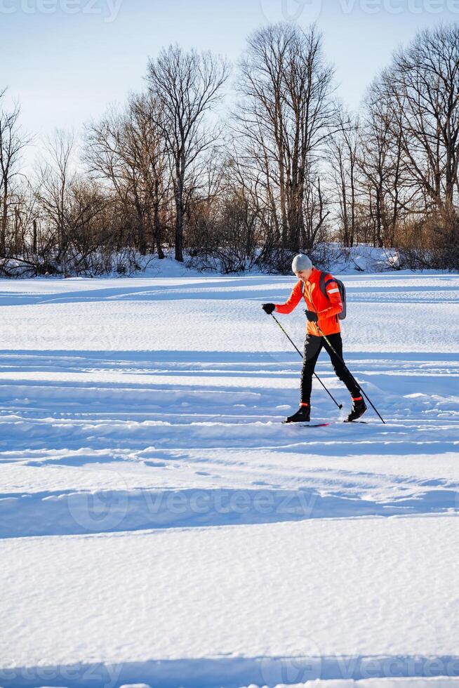 Skier running on skis in snow, training in winter forest, man skiing in nature. photo