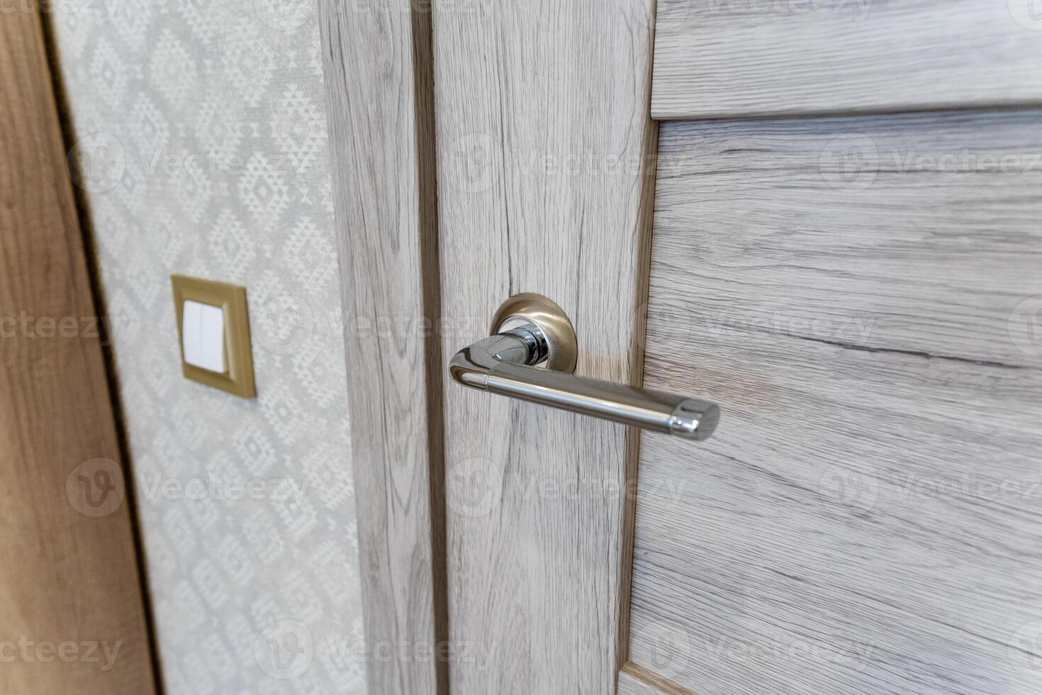 This is a close up image of a beautifully crafted door handle situated on a richly colored wooden door, showcasing the fine details of this household fixture within the entryway photo