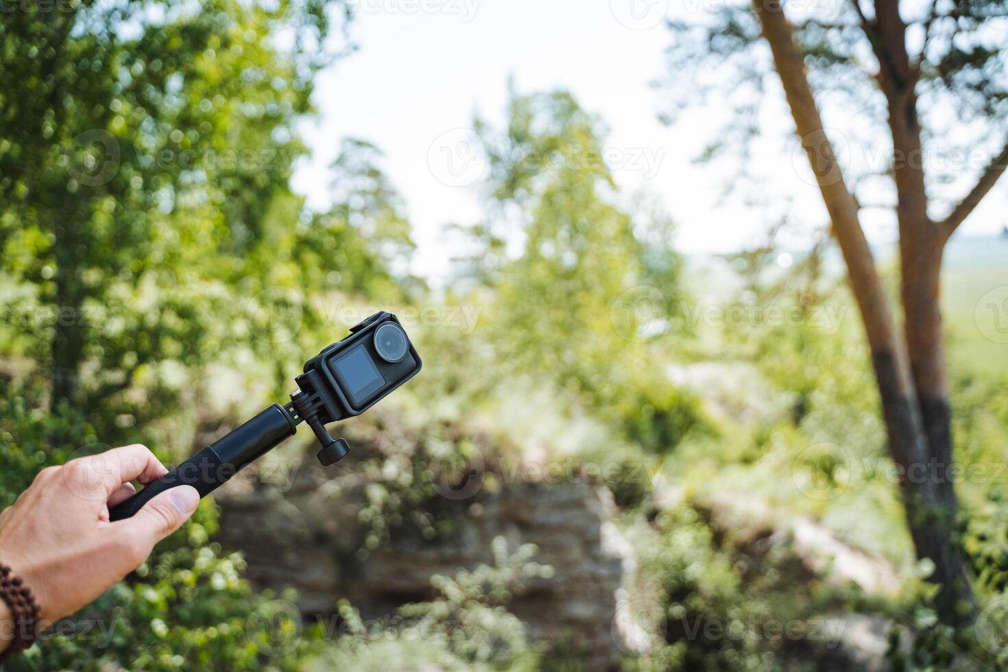 Immersing in the beauty of nature while using an action camera to capture outdoor adventures in a lush forest with stunning scenery and greenery, creating cherished memories photo