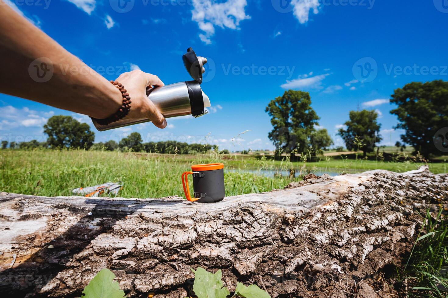 pour tea from a thermos into a mug in nature, a hot drink, metal tourist utensils for trekking. photo