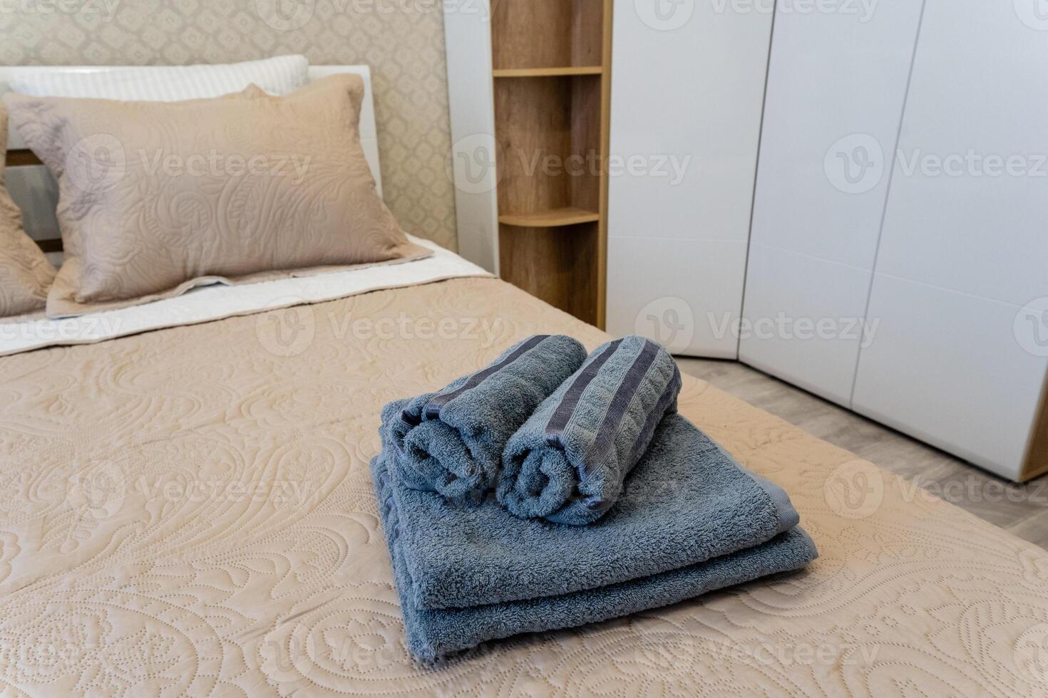 This is a cozy and inviting bedroom featuring neatly rolled towels placed on the bed for added comfort photo