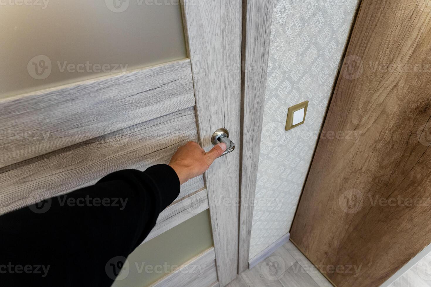 A hand is gracefully reaching out for a sleek door handle within a contemporary, modern interior space setting photo