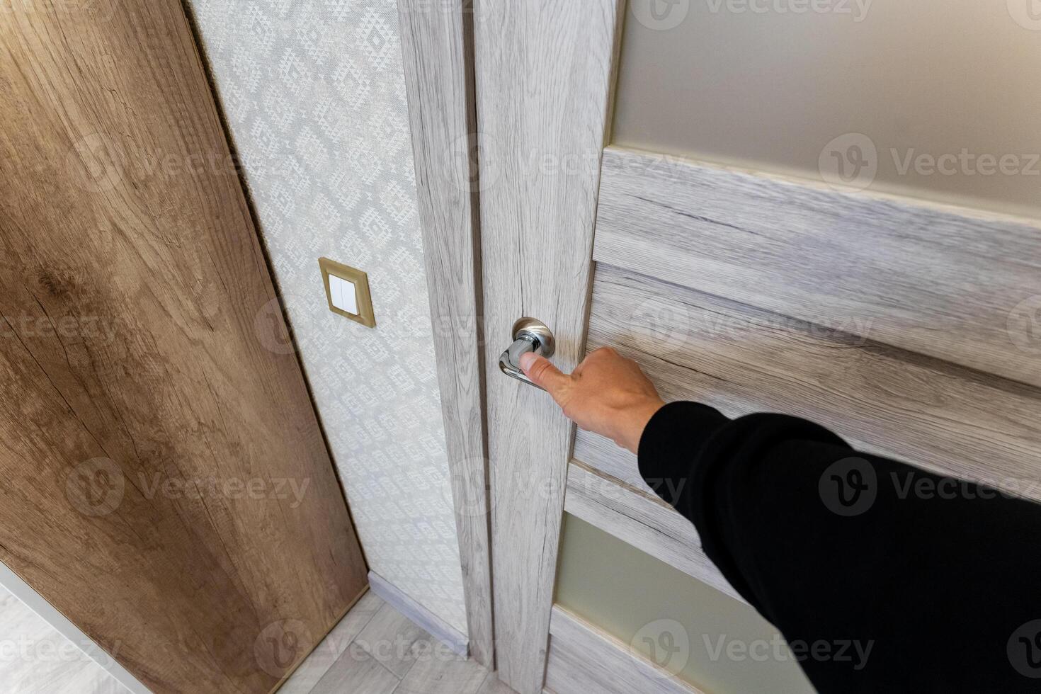A person is using their hand in a deliberate motion to open a door, engaging in a simple yet essential action that permits access to a new space or room that may hold various possibilities photo