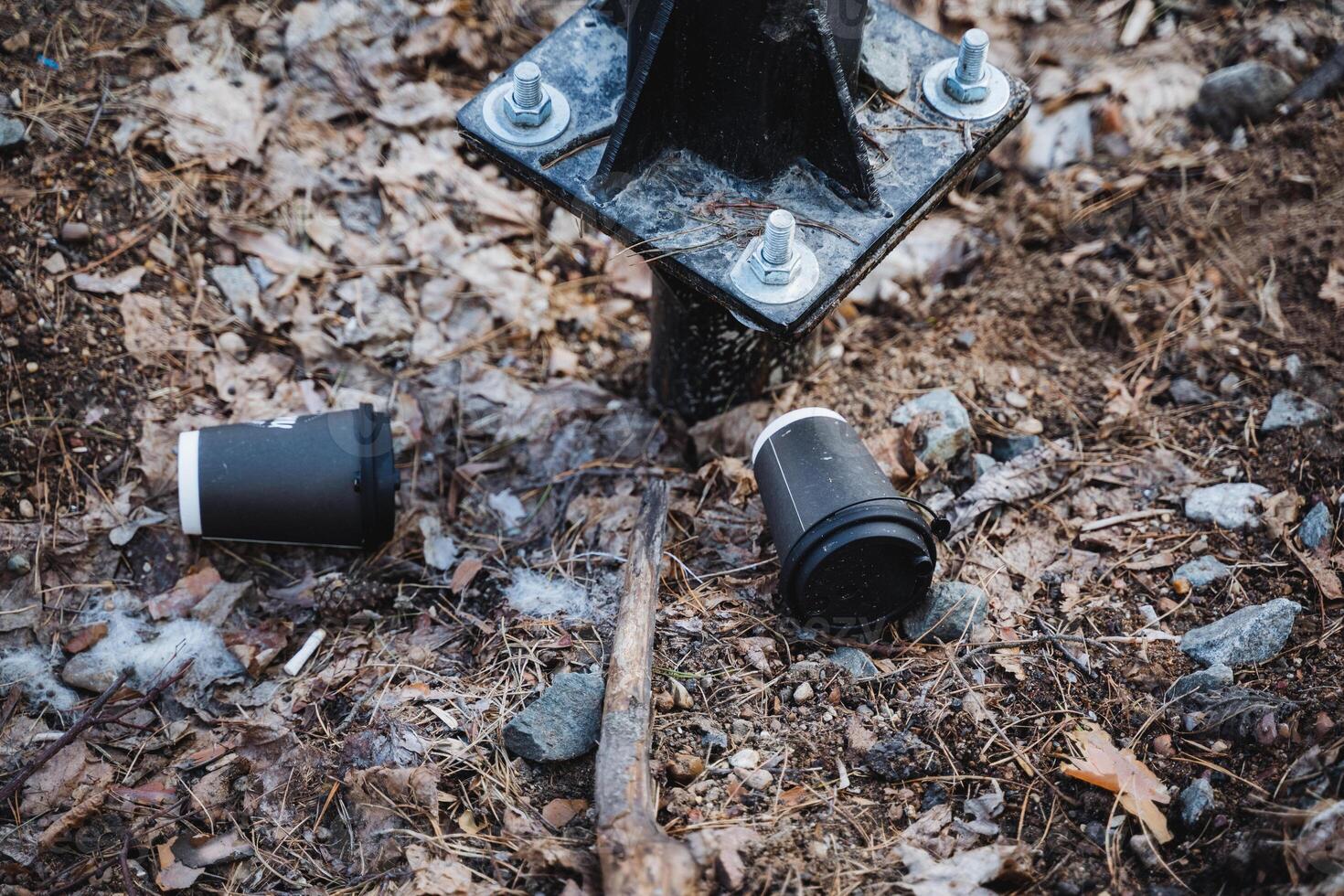 A black automotive tire rests on the ground near a metal post photo