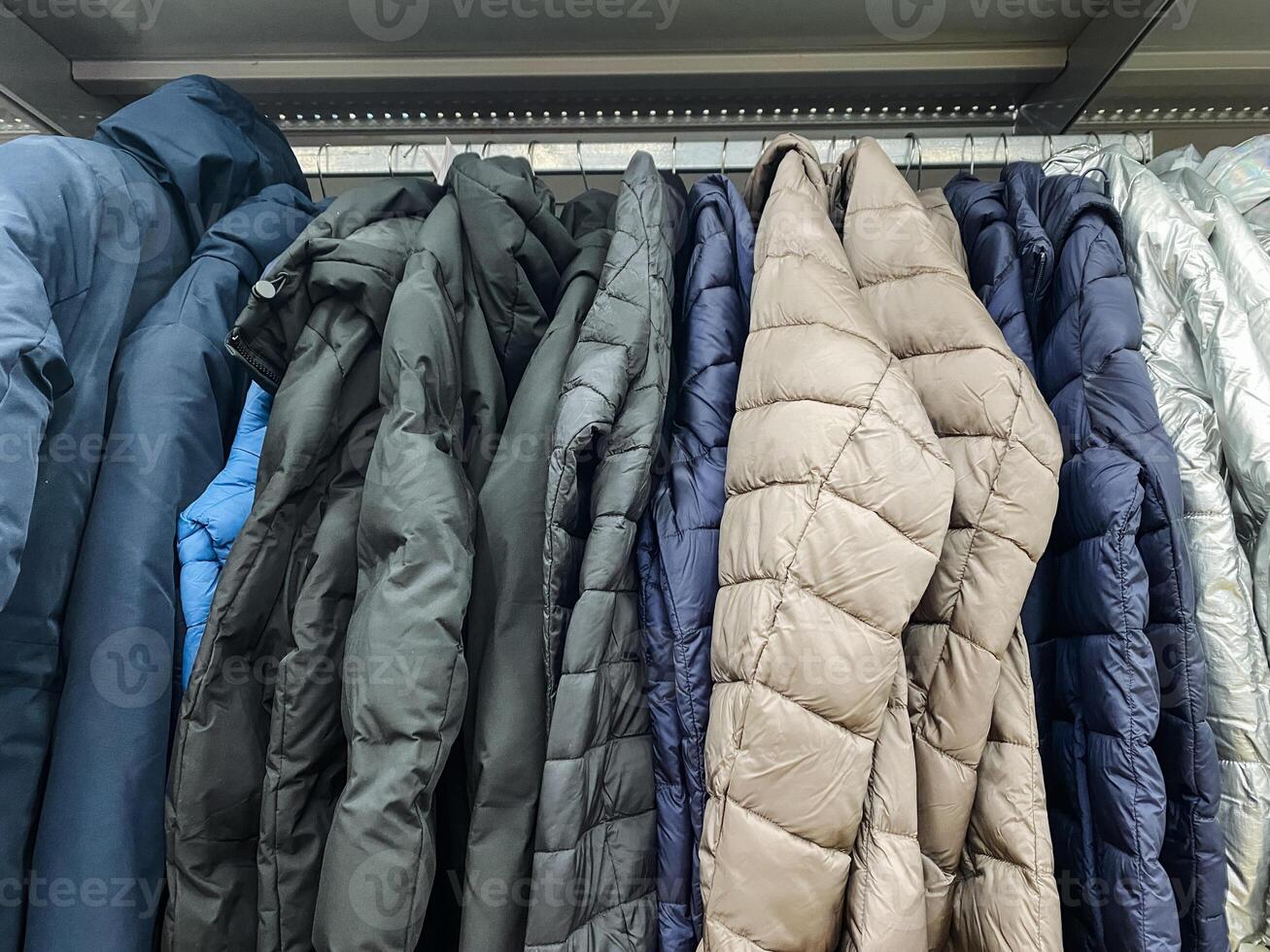 A collection of stylish jackets hangs on a vibrant rack in a colorful store, showcasing unique designs and diverse fabrics for customers to enhance their wardrobe choices photo