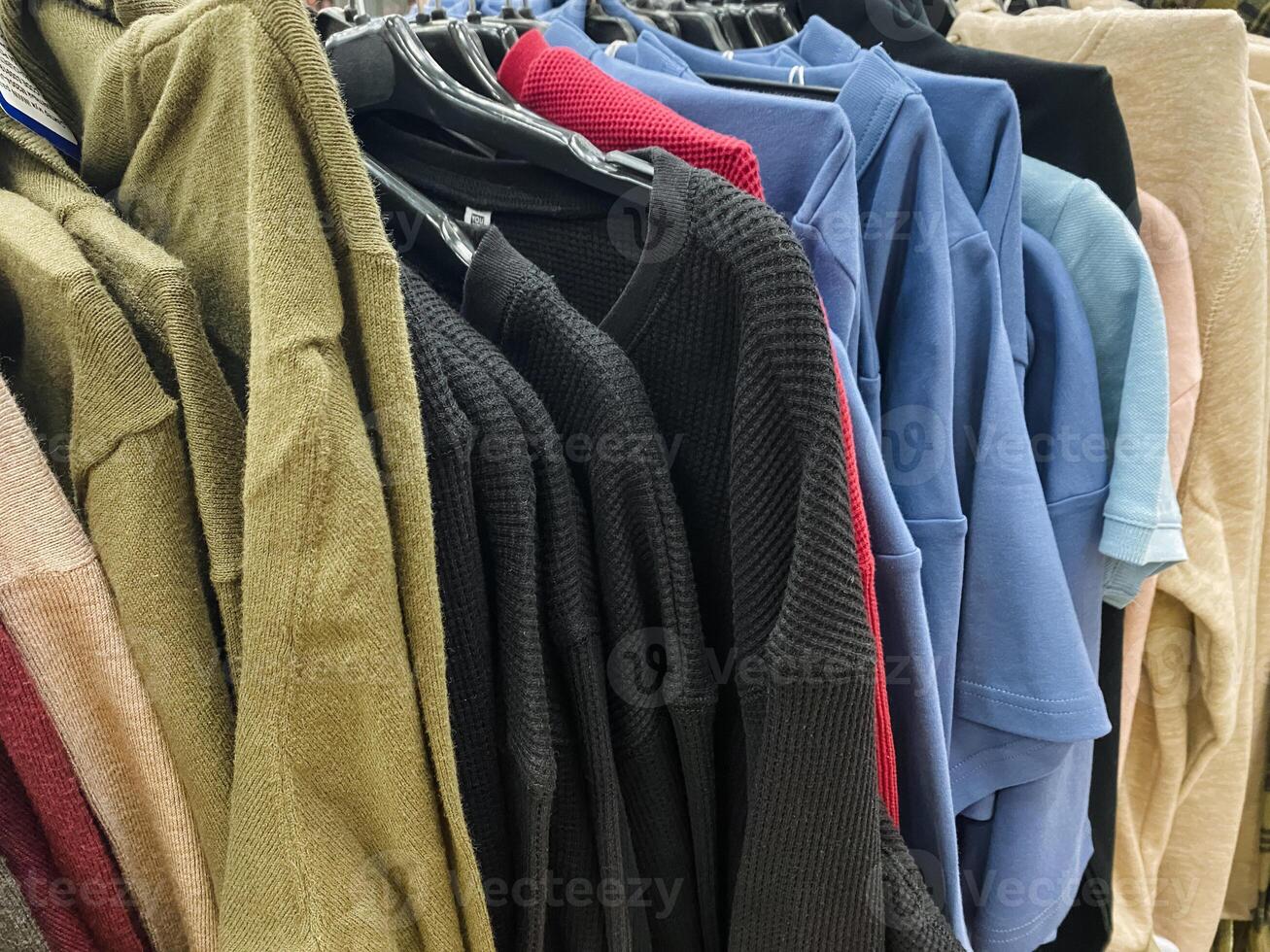 A collection of various clothes, including shirts and pants, are neatly hanging on a sturdy rack, showcasing the latest fashion items available for customers to browse and select from photo