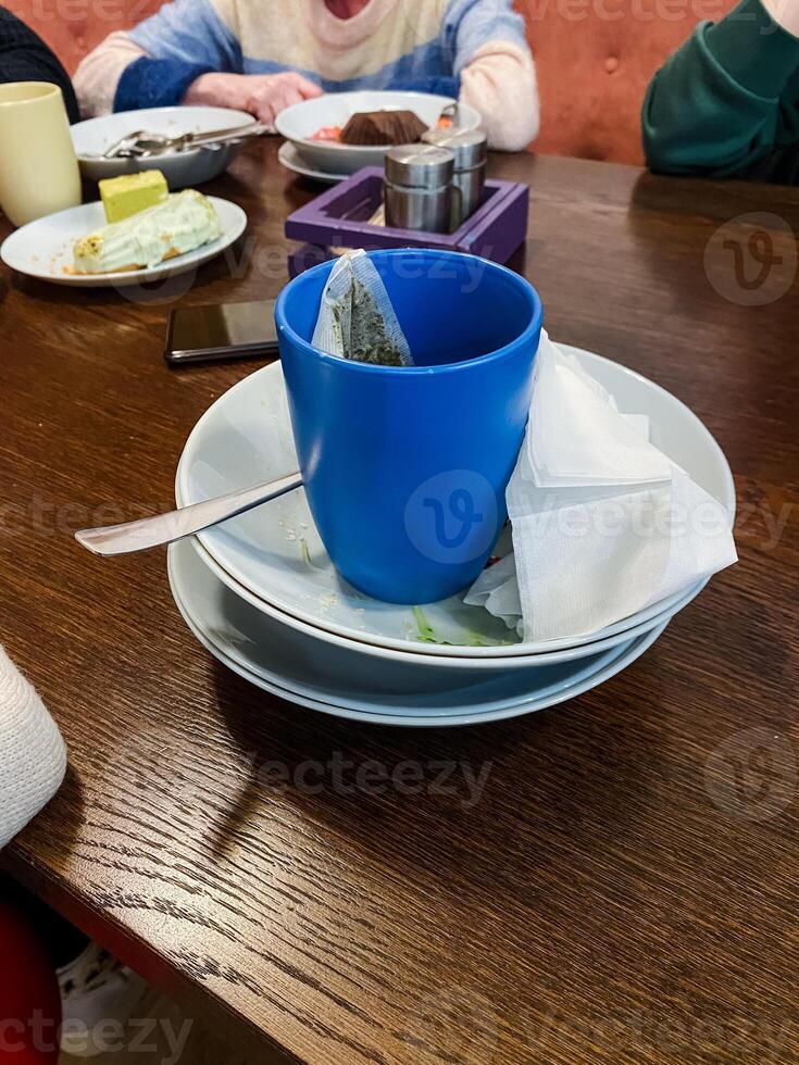 A vibrant blue cup is elegantly placed atop a neatly arranged stack of plates, creating a beautiful display of tableware perfect for any dining setting or special occasion photo