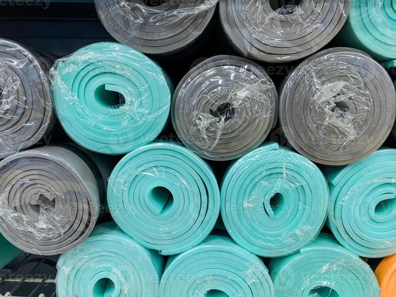 A vibrant and eyecatching stack of yoga mats, made from a variety of colors and different materials, creates a colorful and appealing display of fitness gear for all exercise enthusiasts photo