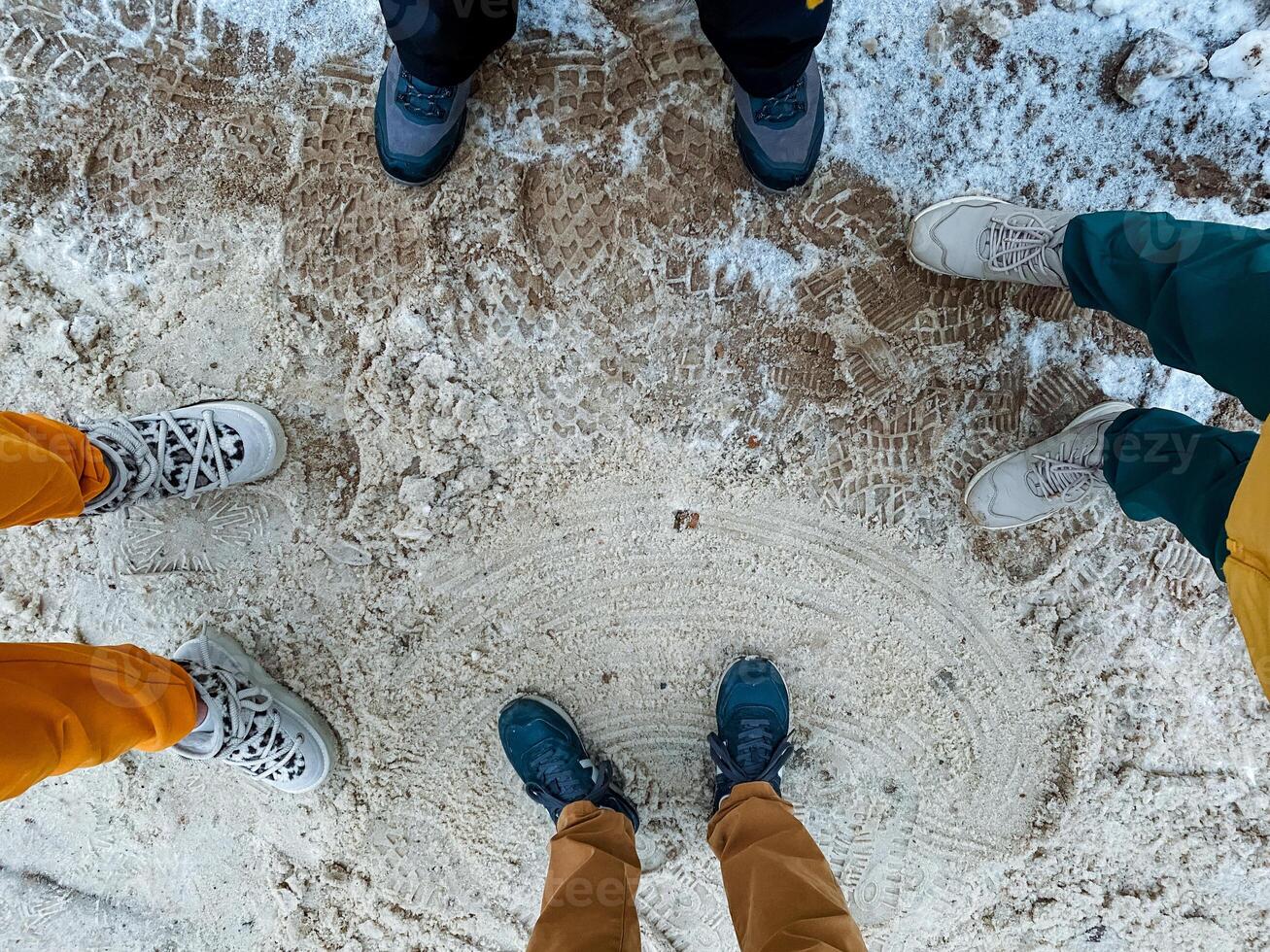 A vibrant and diverse group of individuals stands closely in a circle, surrounded by freshly fallen, glistening snow that beautifully enhances the picturesque wintry scene beneath them photo