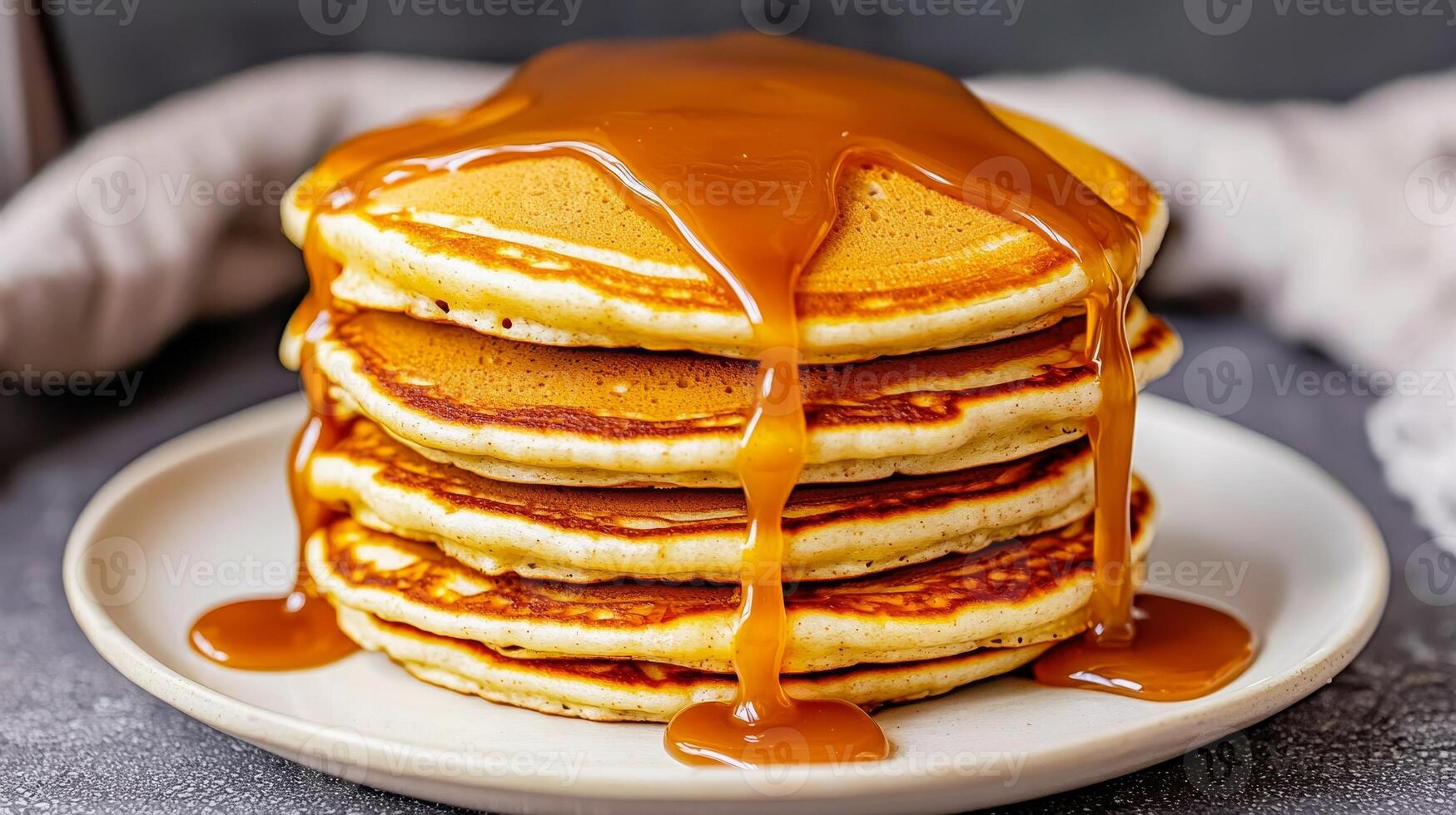 Smooth caramel drizzle. Stack of pancakes drizzled with syrup on a white plate. photo