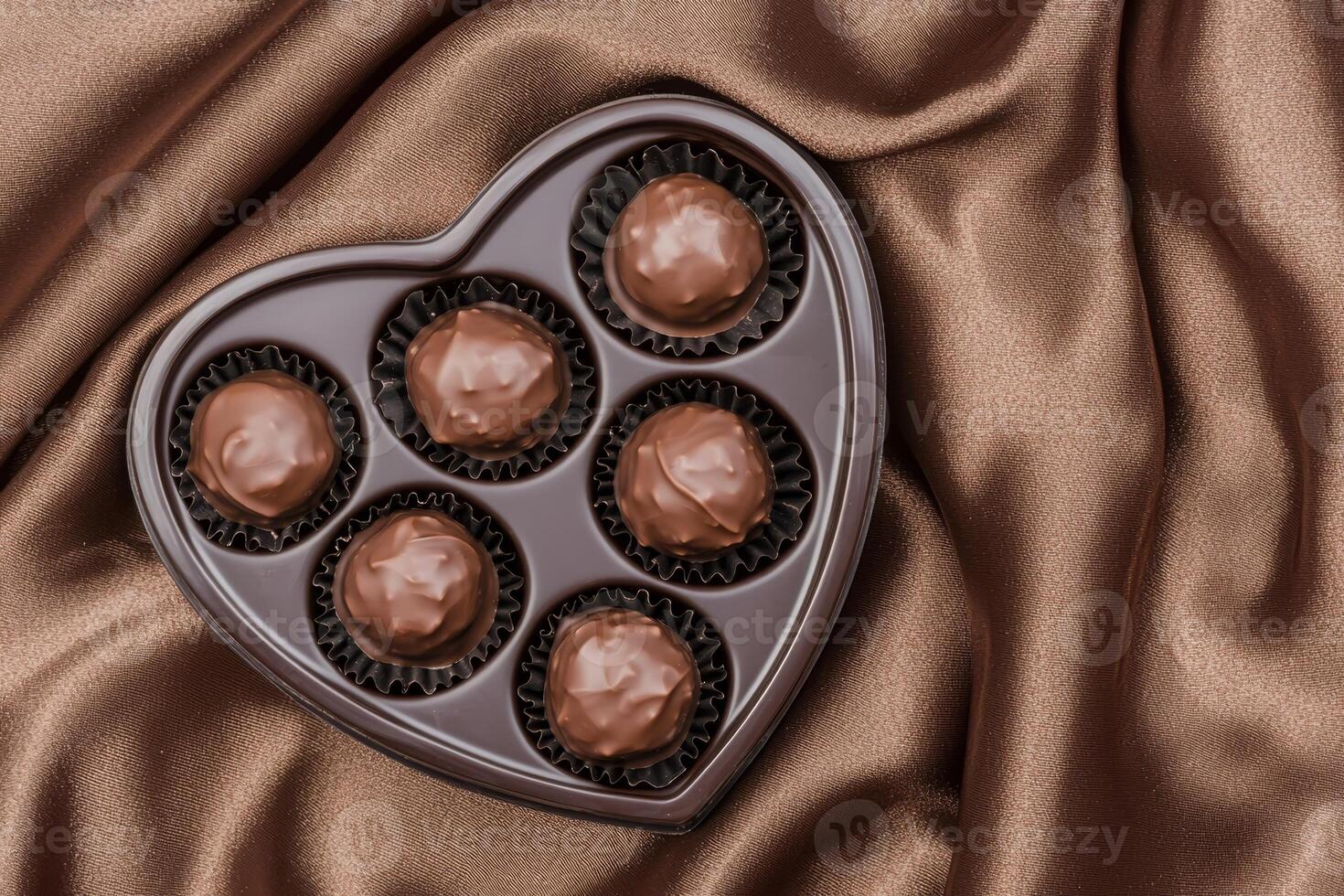 Brown background valentine s day concept. Heart-shaped chocolate box on a satin fabric background. photo