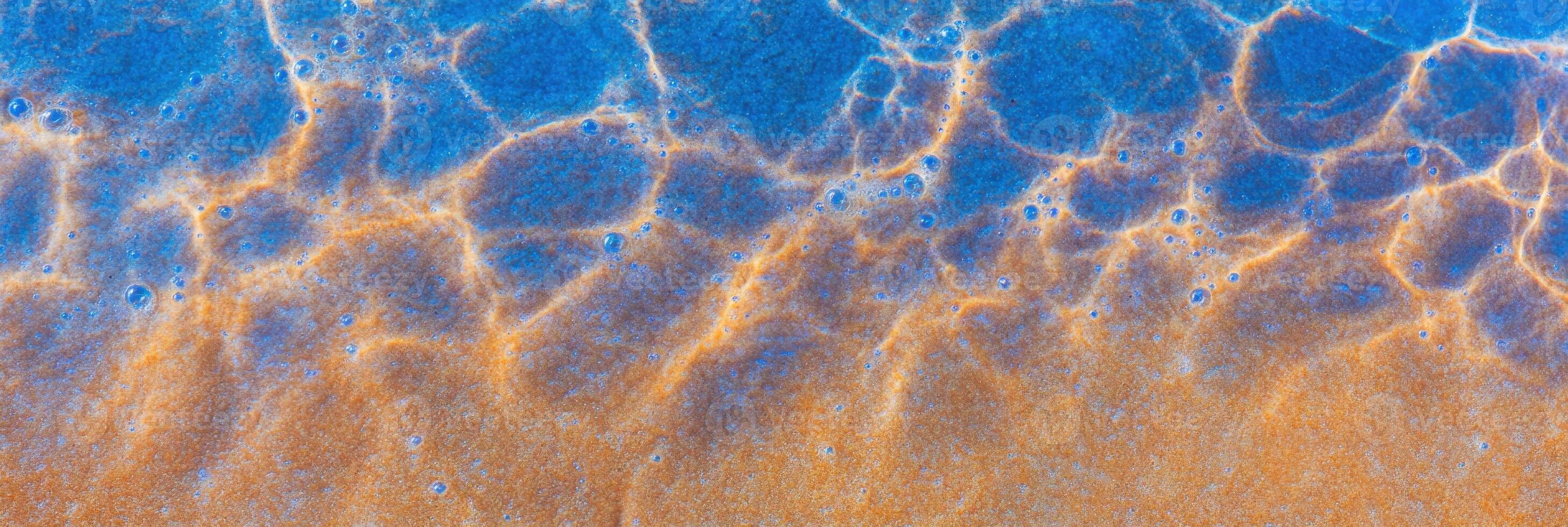 Aerial view of vibrant ocean waves and sandy shore with rippling patterns photo